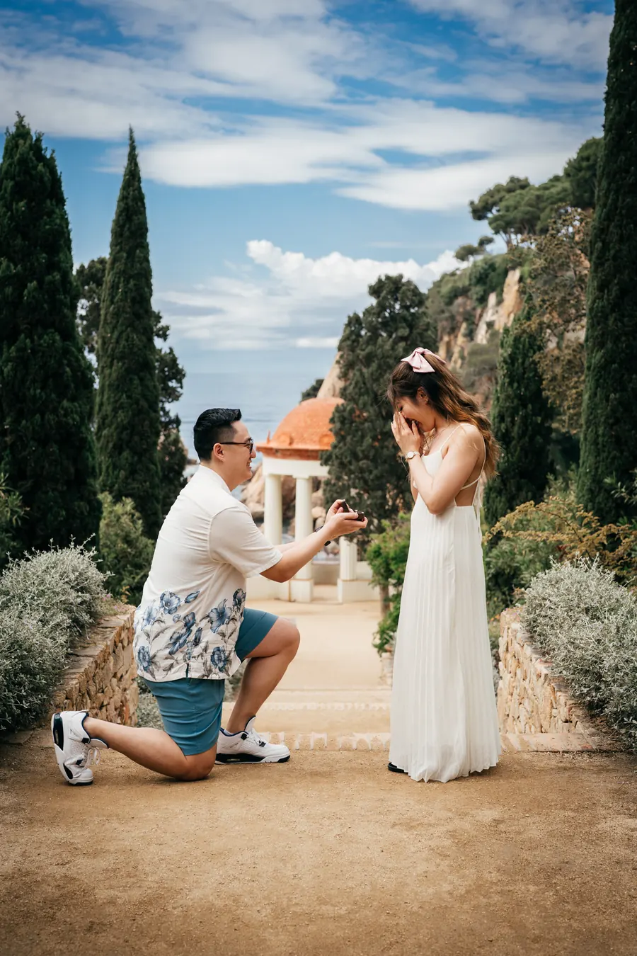 He kneels on the path at Marimurtra and she covers her face